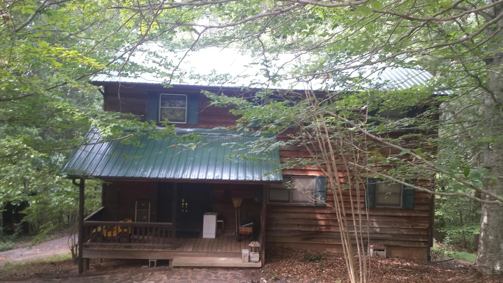 Green metal roof and covered porch on a log cabin in Blakesburg