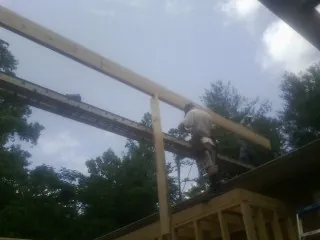 Carpenter setting a ridge beam over a new addition frame — Ice Dam Removal by Roofing Brothers in Blakesburg