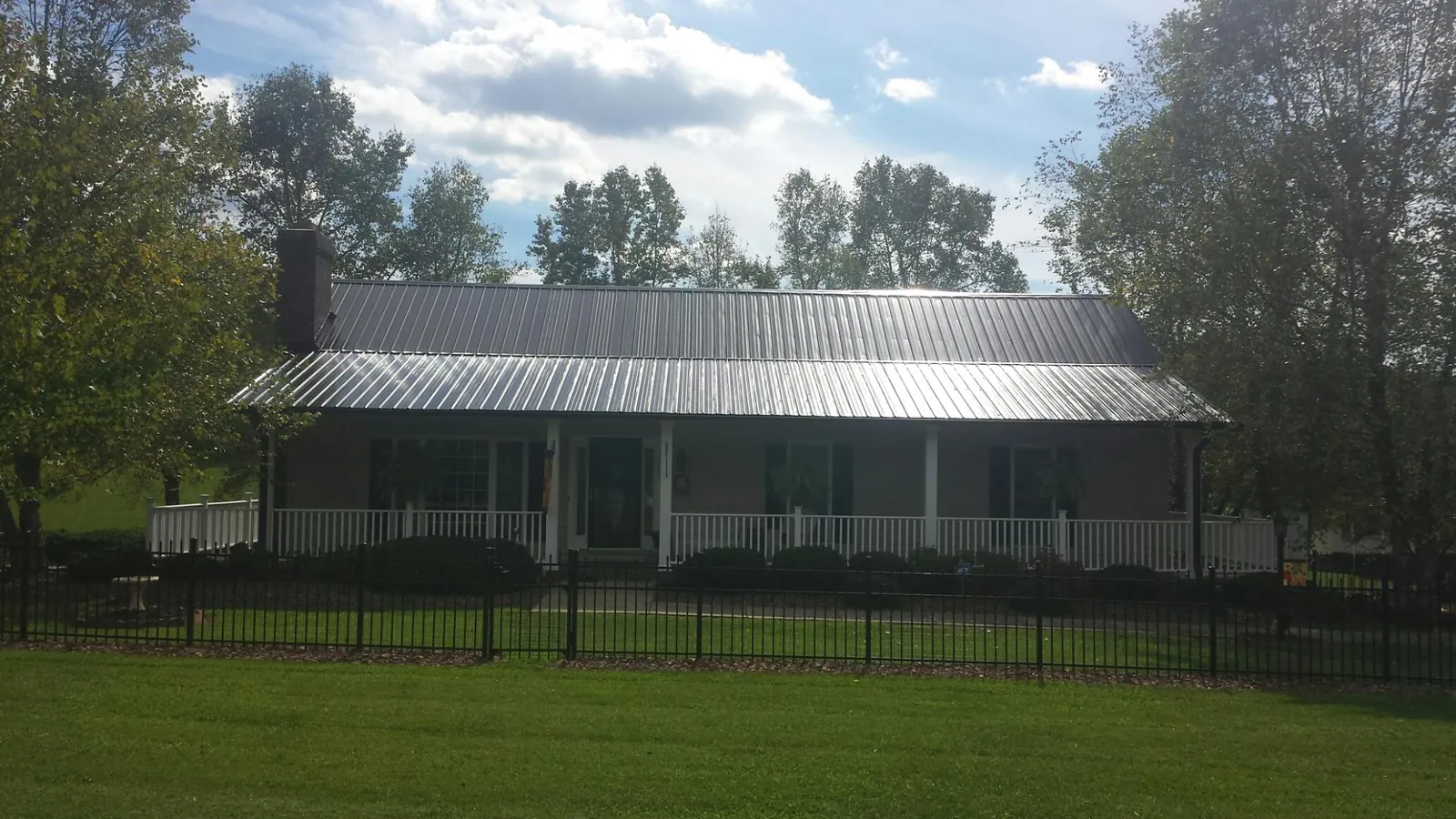 Gray metal roof on a brick ranch with a full width front porch — Gutter Guard Installation work by our crew in Blakesburg