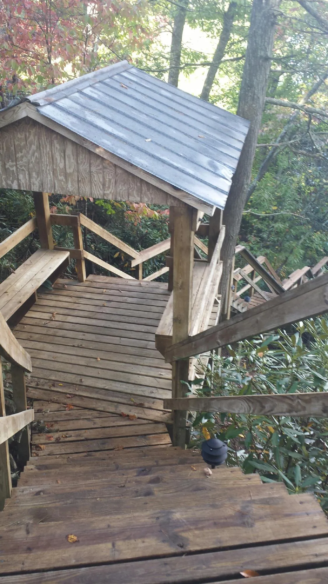 Metal roofed shelter over wooden steps on a wooded walkway — Skylight Repair & Installation work by our crew in Blakesburg