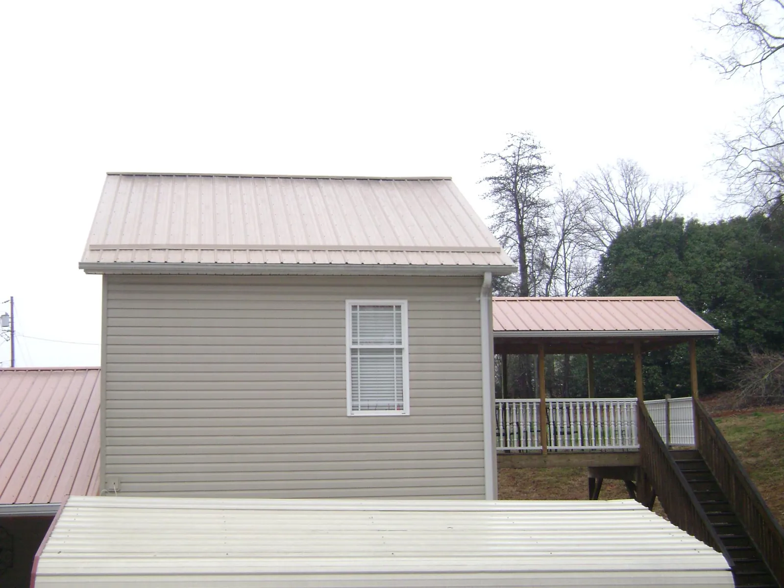 Tan metal roofs on a two story addition and attached porch, from a Roof Replacement job in Blakesburg