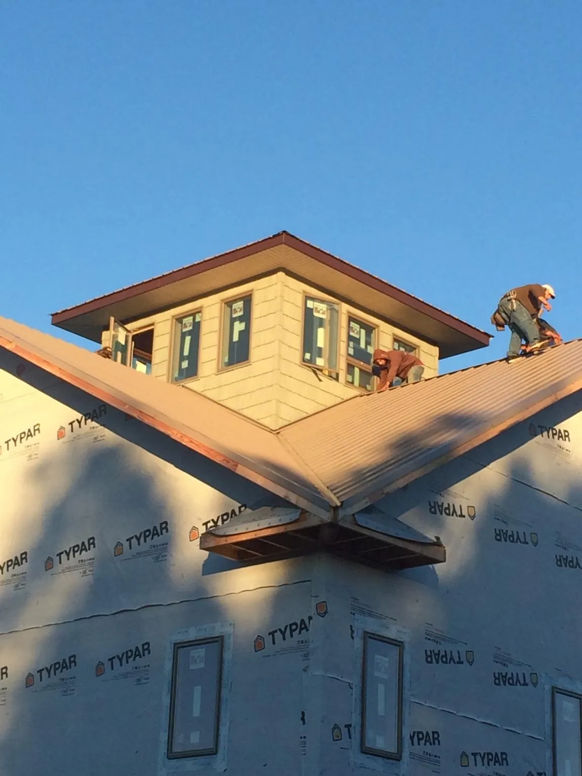 Roofers working around a rooftop cupola on a new metal roof at sunset — Roof Waterproofing in Blakesburg by Roofing Brothers